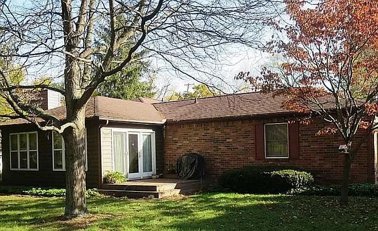 Brick exterior with deck and plenty of foliage
