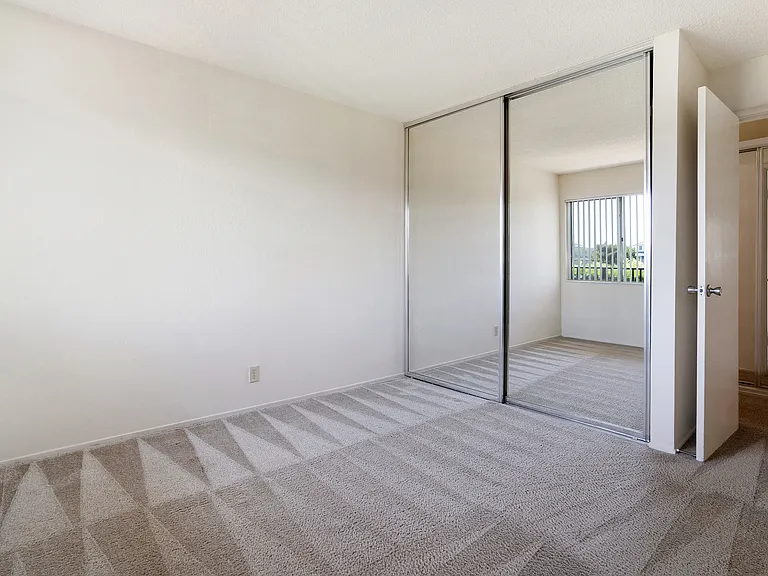 A bedroom with mirrored closet doors.