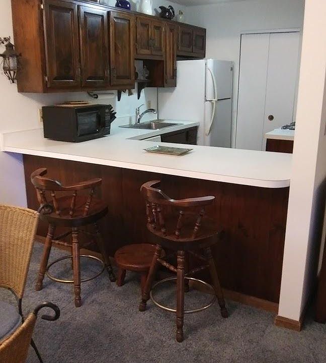 Kitchen with eat at counter and bar stools. Microwave, refrigerator, dishwasher, gas stove.