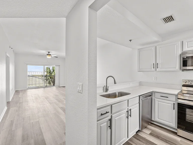 Bright and airy apartment with sleek white kitchen, modern stainless steel appliances, and inviting open living space.