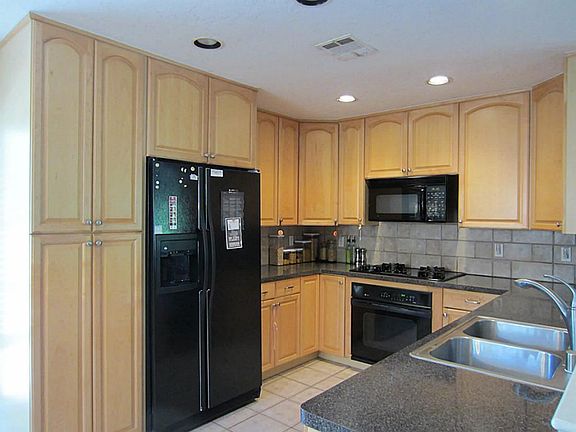 Convenient kitchen with custom cabinetry, gas range, and black appliances.