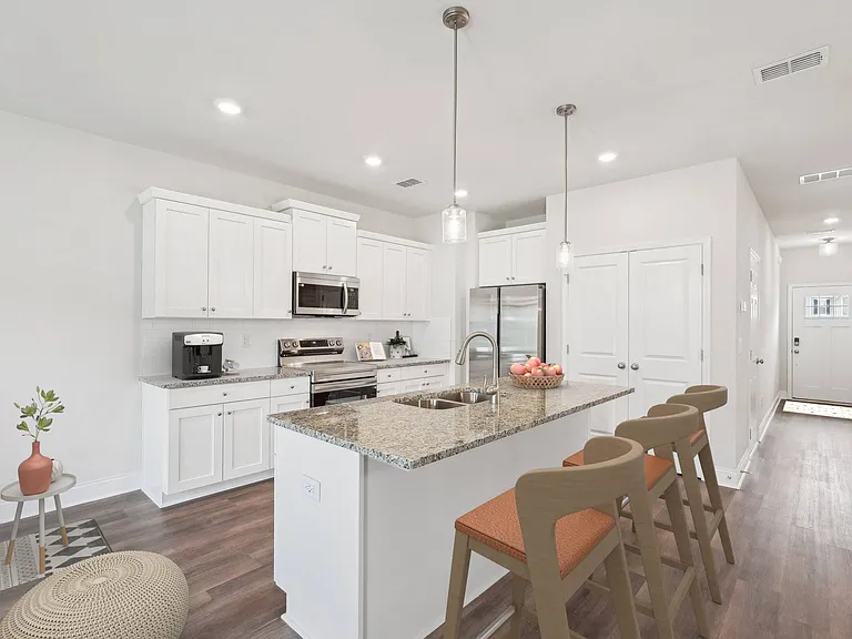 A modern kitchen showcasing a granite countertop island with bar seating and premium stainless steel appliances.