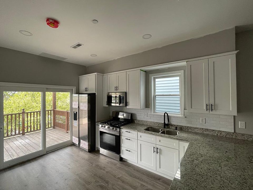 Unit two: open-concept kitchen with all new appliances, cabinets, granite, and finishings and view of private patio/deck.