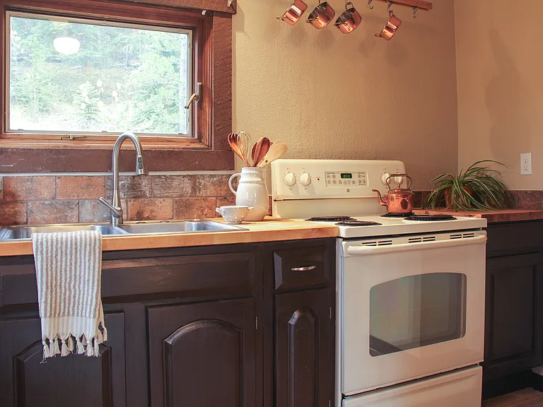 Hanging pot rack and double sink with a view of nature