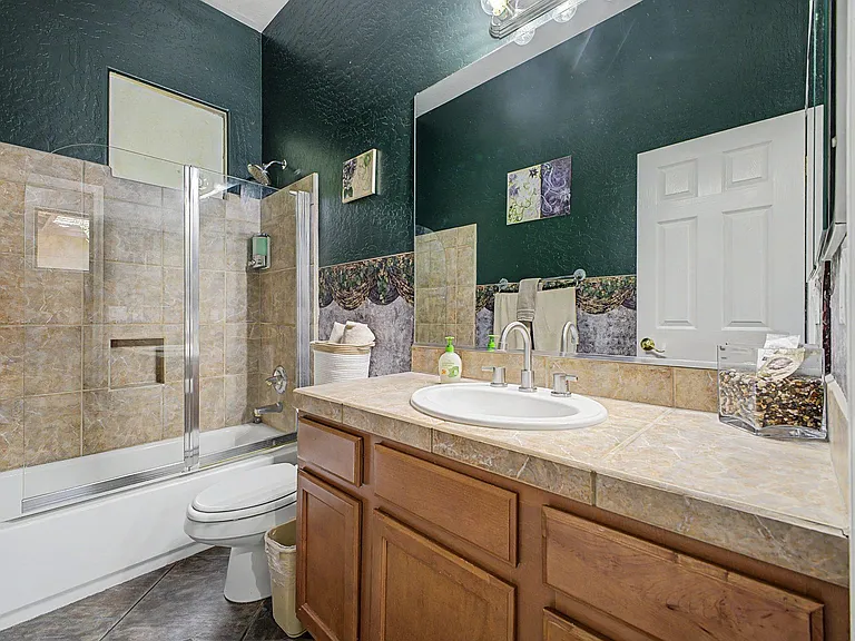 Full bath with tiled tub/shower, wide vanity counter, and ample cabinet storage for daily essentials.