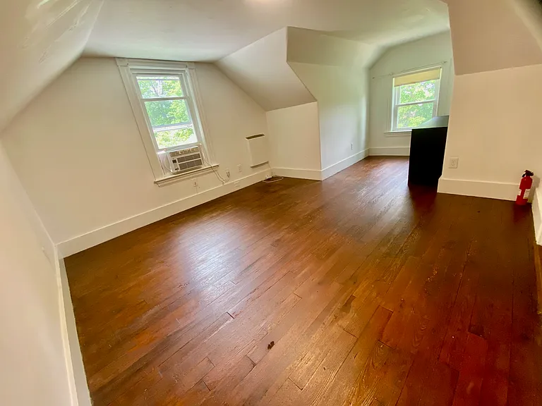Attic room with a dormer and views of trees.