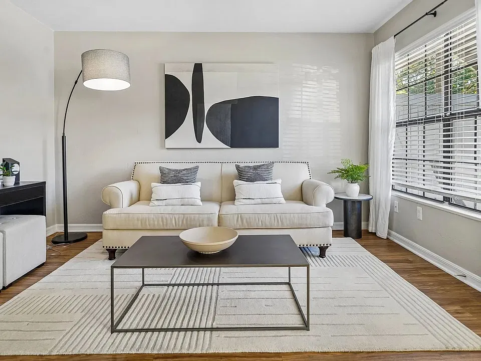 Make yourself at home in a bright and inviting living room featuring wood-style flooring, oversized windows, and an open layout that provides plenty of space to relax, entertain, or unwind.