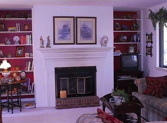 Living room boasts gas log fireplace with built in bookshelves on either side.