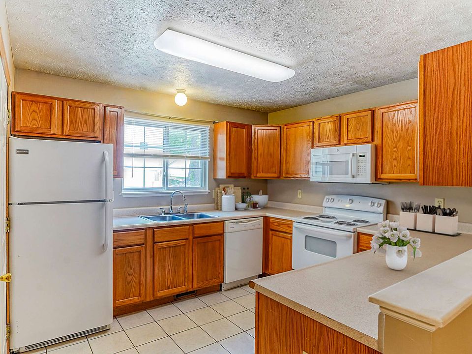A spacious kitchen featuring a refrigerator, gas stove, wooden cabinets.