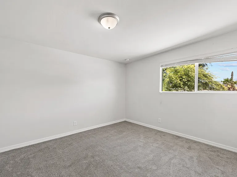 Fourth bedroom offers a peaceful retreat with a view of the mature trees outside.