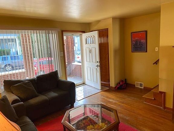 Living room with newly-refinished hardwood floors and coat closet.