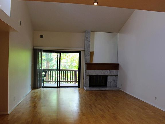 Living room with gas fireplace, sliding door to oversized balcony and vaulted ceilings.