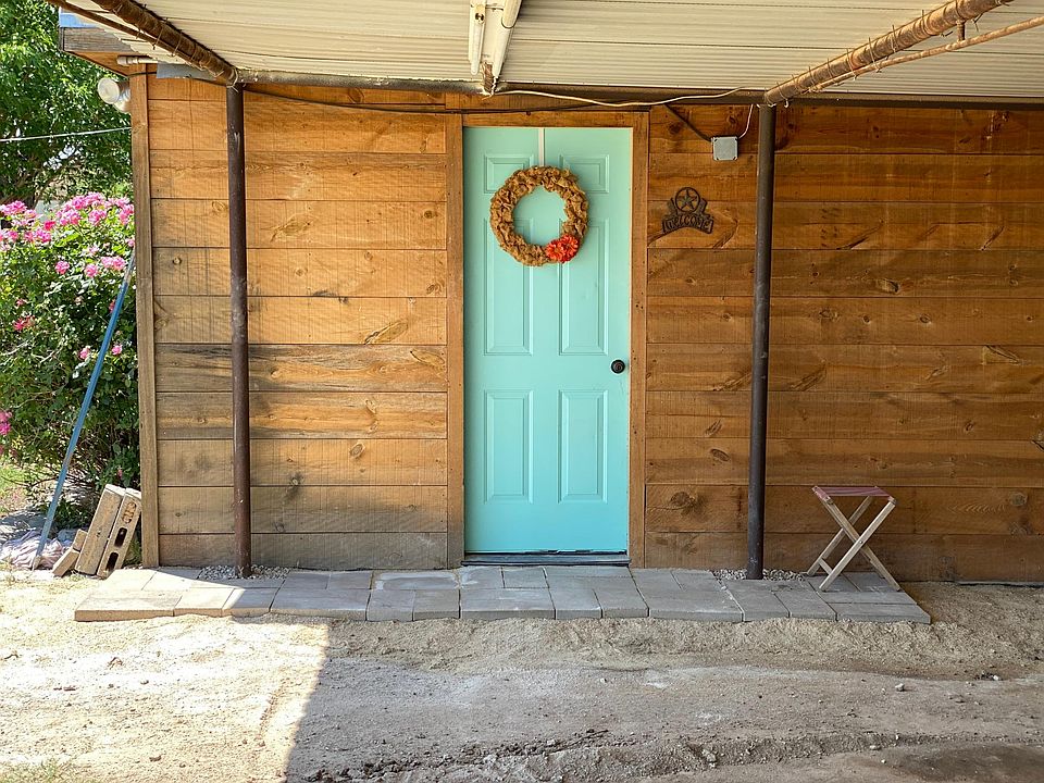 View from covered parking. Front door with small stoop/porch. Covered parking also has lighting under it.