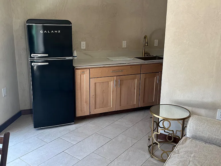 Kitchenette with full-size refrigerator, sink, and generous counter space, plus lower cabinet storage and tile flooring.