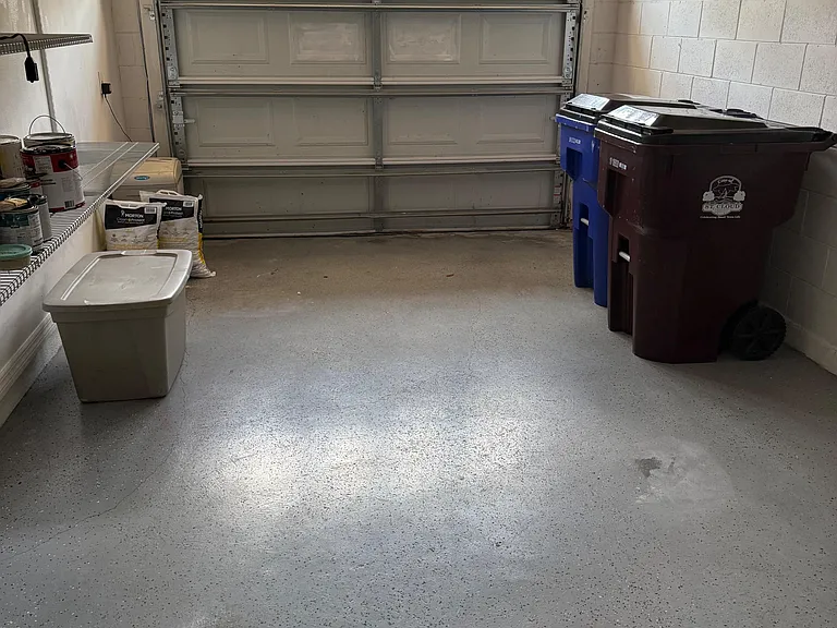 Spacious attached garage with durable sealed flooring, built-in shelving, and room for bikes, bins, or extra storage.