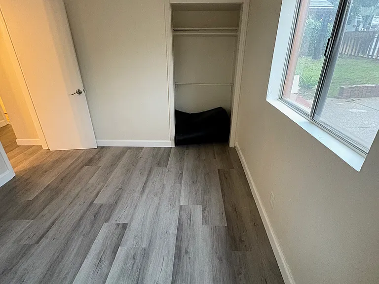Inside bedroom, looking at closet on the right and entry door on the left.