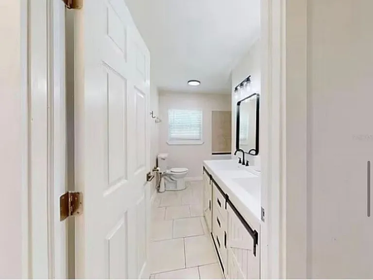Newly updated full bathroom with modern black fixtures, white vanity, tile flooring, and natural light