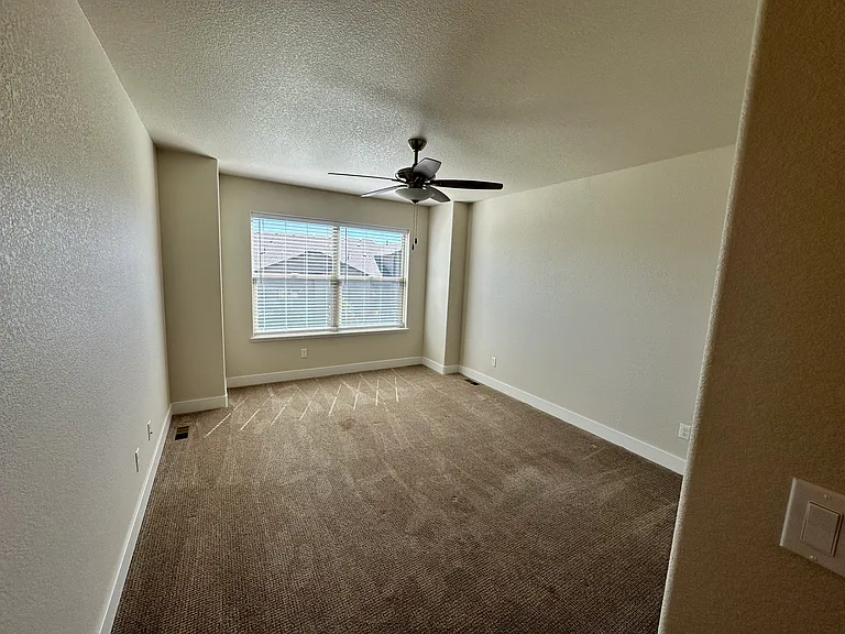 Master bedroom on main floor with fan and window coverings.