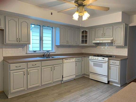 Updated kitchen with gray cabinets, new gray tiled flooring, white tile backsplash and dishwasher.