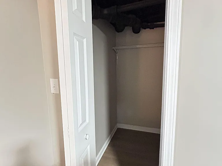 Reach-in closet with hanging rod and shelf, offering convenient storage space for clothing and everyday essentials.