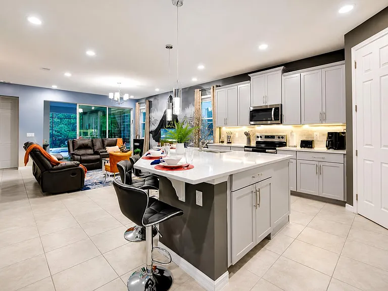 Open-concept kitchen with a large island and bar seating, stainless appliances, and ample cabinetry flowing into the living a