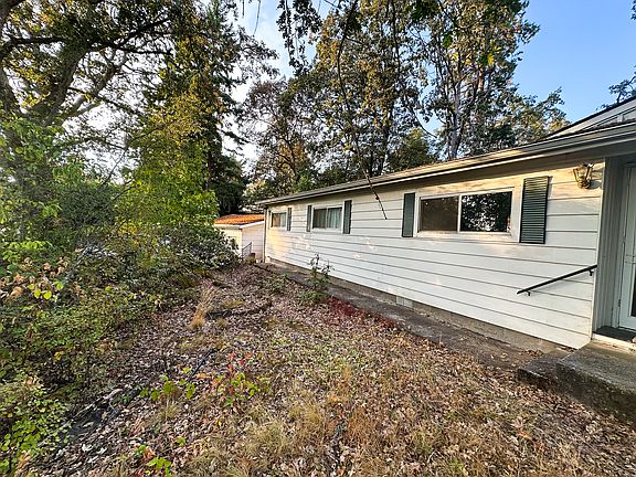 Front Side: Nestled high on a quiet rise, this home feels like it's perched at the edge of a forest dream.The low-maintenance front yard is a tapestry of moss, leaves, and ferns_a living artwork that shifts with the seasons and invites a slower pace.