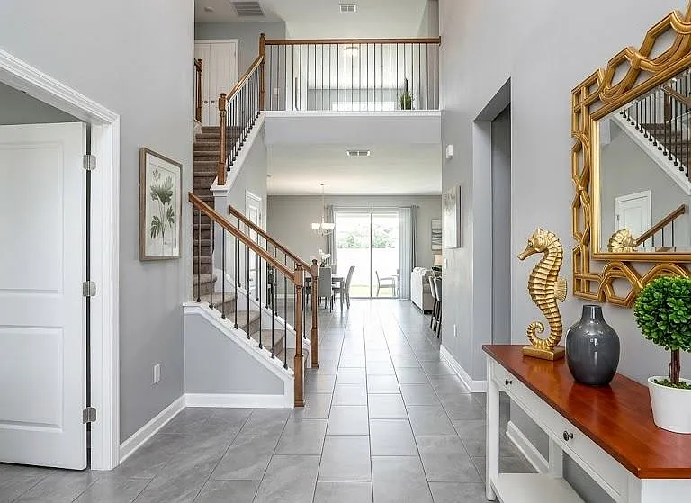 Spacious entry foyer with tiled floors, staircase to an open landing, and a clear sightline to the dining area and patio door