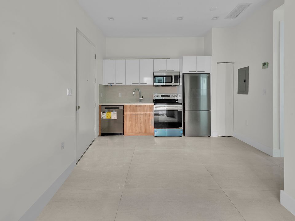 Kitchen with stainless steel appliances and chrome finishes: refrigerator, dishwasher, microwave, and deep sink. View from living area.
