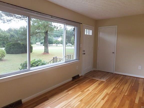 Large living room with beautiful refinished hardwood floor,entrance closet, and triple windows for lots of sunshine!