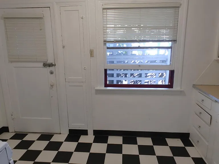 The dual-paned kitchen window looks out on a small back yard. There's a built-in ironing board neard the back door/