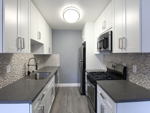Kitchen with quartz stone counters and stainless steel microwave, oven, fridge, and fixtures.