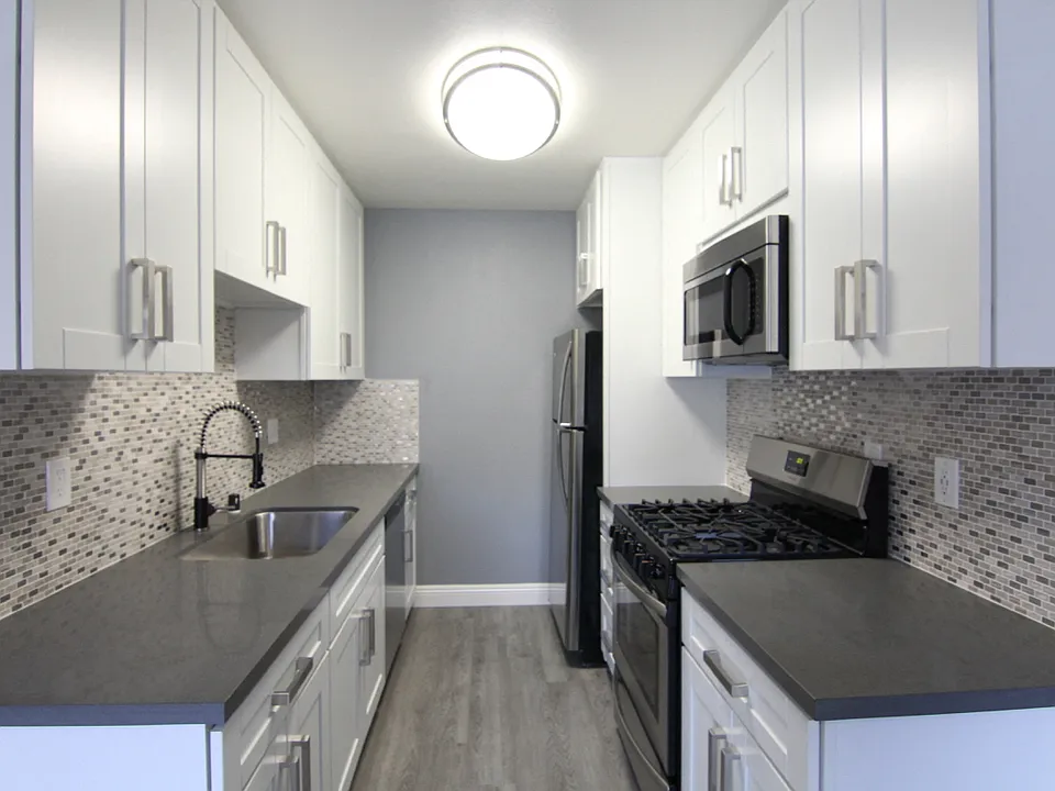 Kitchen with quartz stone counters and stainless steel microwave, oven, fridge, and fixtures.