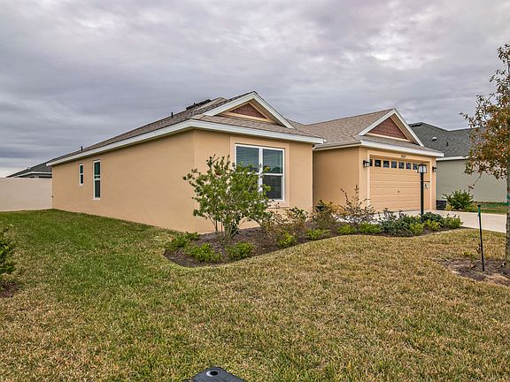 Front View of the House with Side Yard and the Primary Bedroom Window, as well as the Secondary Bedroom Windows.