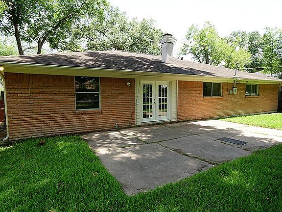 Back view with open concrete patio and exterior lighting