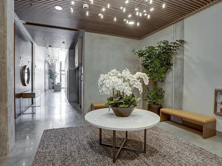Lobby hallway with modern lighting, greenery, and a central table featuring fresh floral decor.