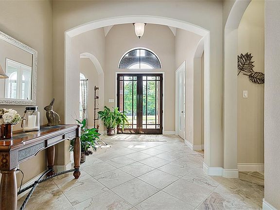 The True Divided Light Double doors with the half moon window, wide hallway, tall ceilings and archways create a dramatic foyer.
