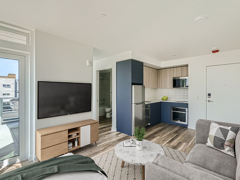 Experience the open and inviting living space at Anker Ballard, featuring modern furniture, a spacious layout, and a seamless transition between the living room and kitchen.