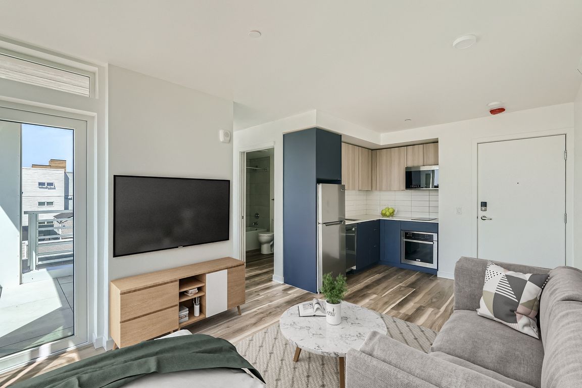 Experience the open and inviting living space at Anker Ballard, featuring modern furniture, a spacious layout, and a seamless transition between the living room and kitchen.