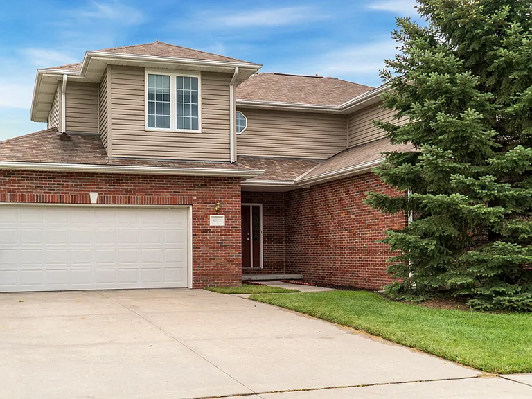 A welcoming drive leads to you two-car garage, framed by a tranquil front yard and towering pine.