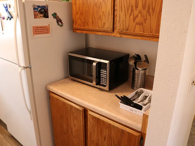 kitchen area with microwave and cupboards. there are dishes and cookware in each cupboard. (if you want any items removed, please let manager know)
