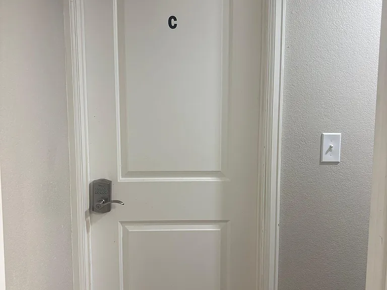 Secure interior entry with keypad lock and neutral finishes, offering convenient access to the room.
