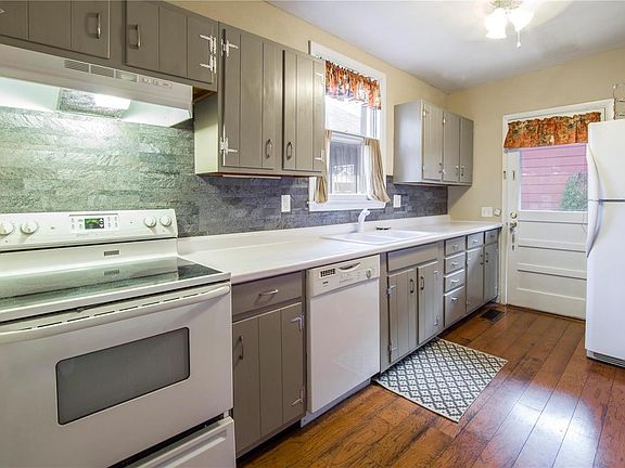 Kitchen boasts original hardwood floors, freshly painted neutral cabinets with new stainless hardware, bright white appliances (refrigerator stays), refinished white counters, backsplash, above-sink window and door window let lots of natural light in. Door leads to backyard and detached garage.