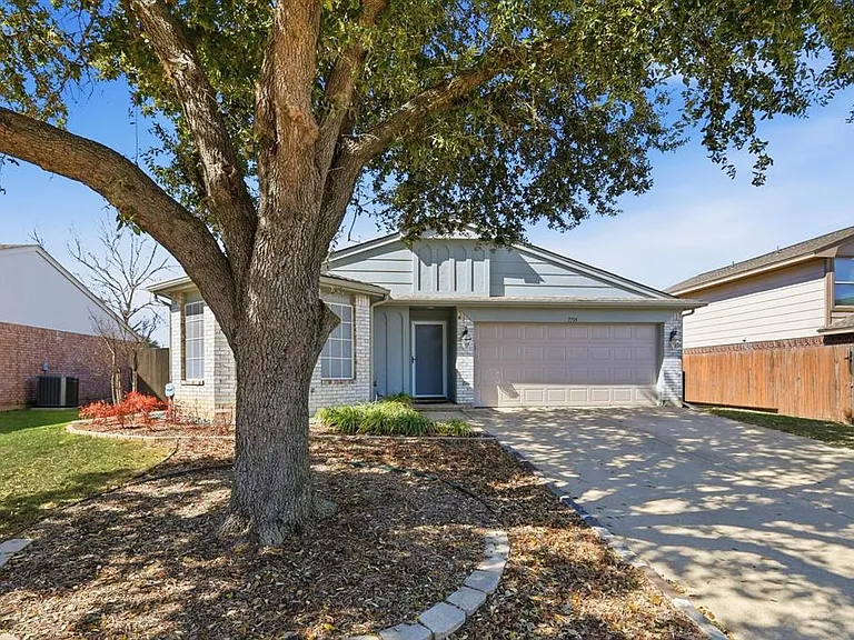 Ranch-style home featuring an attached garage, driveway, and brick siding