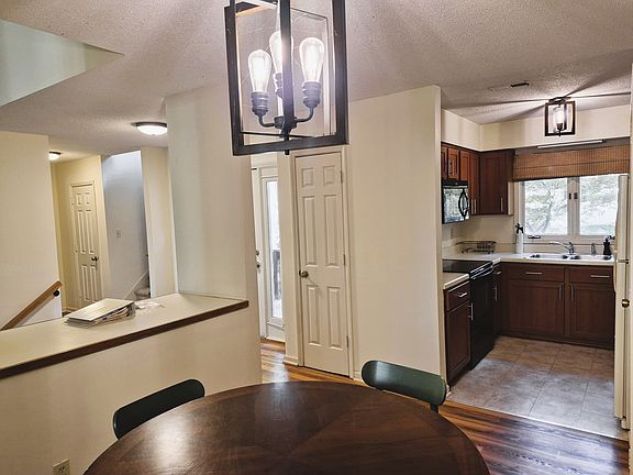 view from the dining room of the kitchen, front door, and staircase with adjacent storage closet