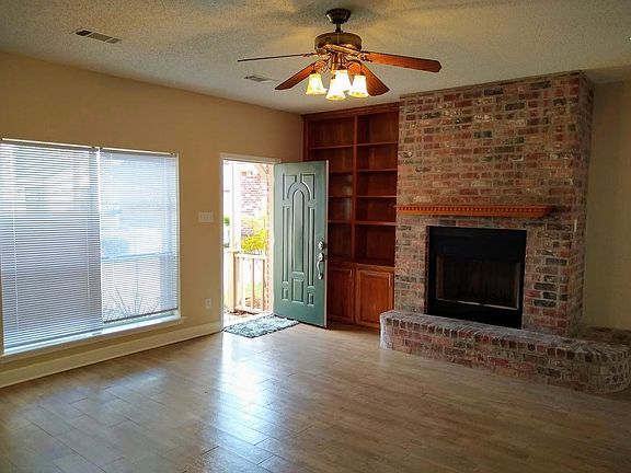Main entrance with wood burning fireplace, large windows, ceiling fan.