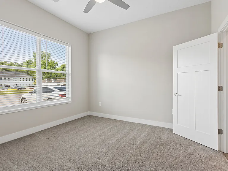 Carpeted bedroom with ceiling fan of a Tiffany Flats apartment home.