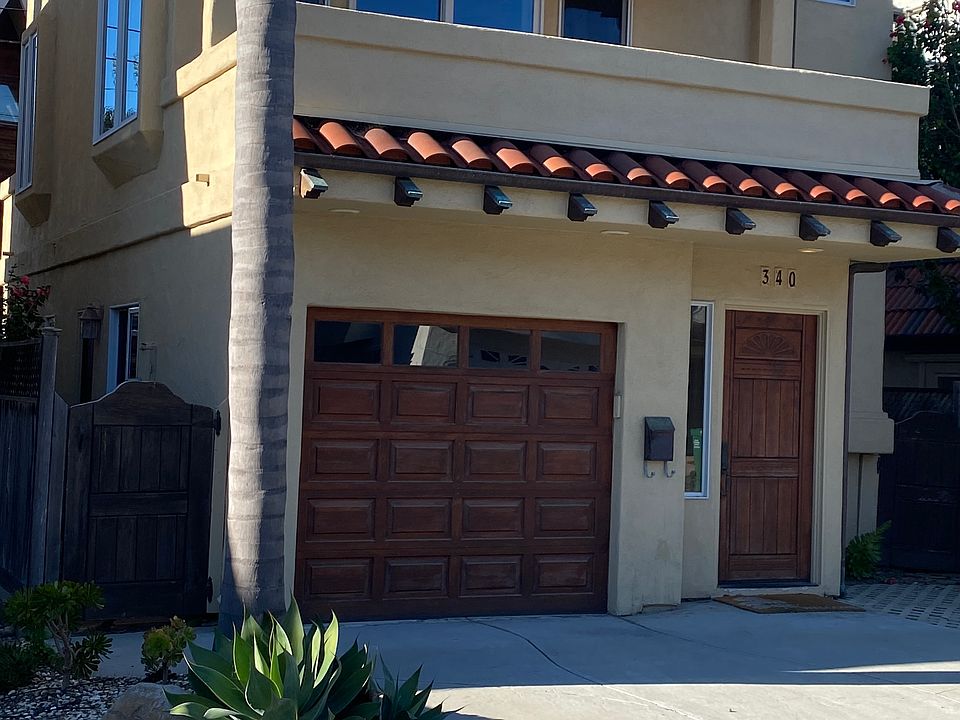 - Front View _ Mediterranean-style facade with red-tile roof and custom wood garage doors.