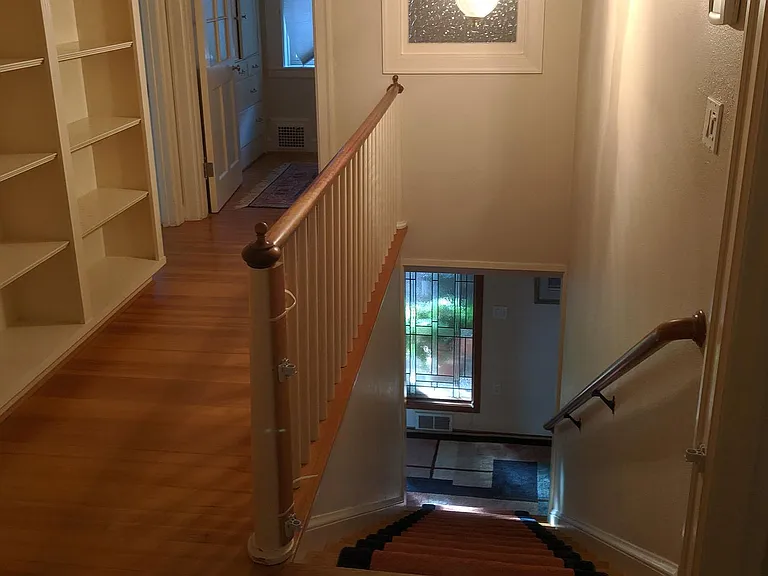 Carpeted stairwell over wood flooring. Built in bookshelf, Little bonus office with large built in linen closet