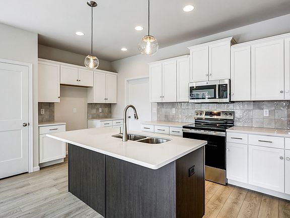 Kitchen with white cabinets and center island in the Adalee Floorplan from Garman Builders