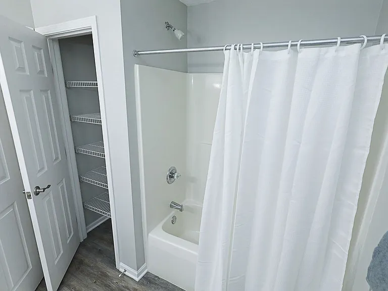 Fresh, clean bathroom with full tub and convenient built-in shelving for extra storage.